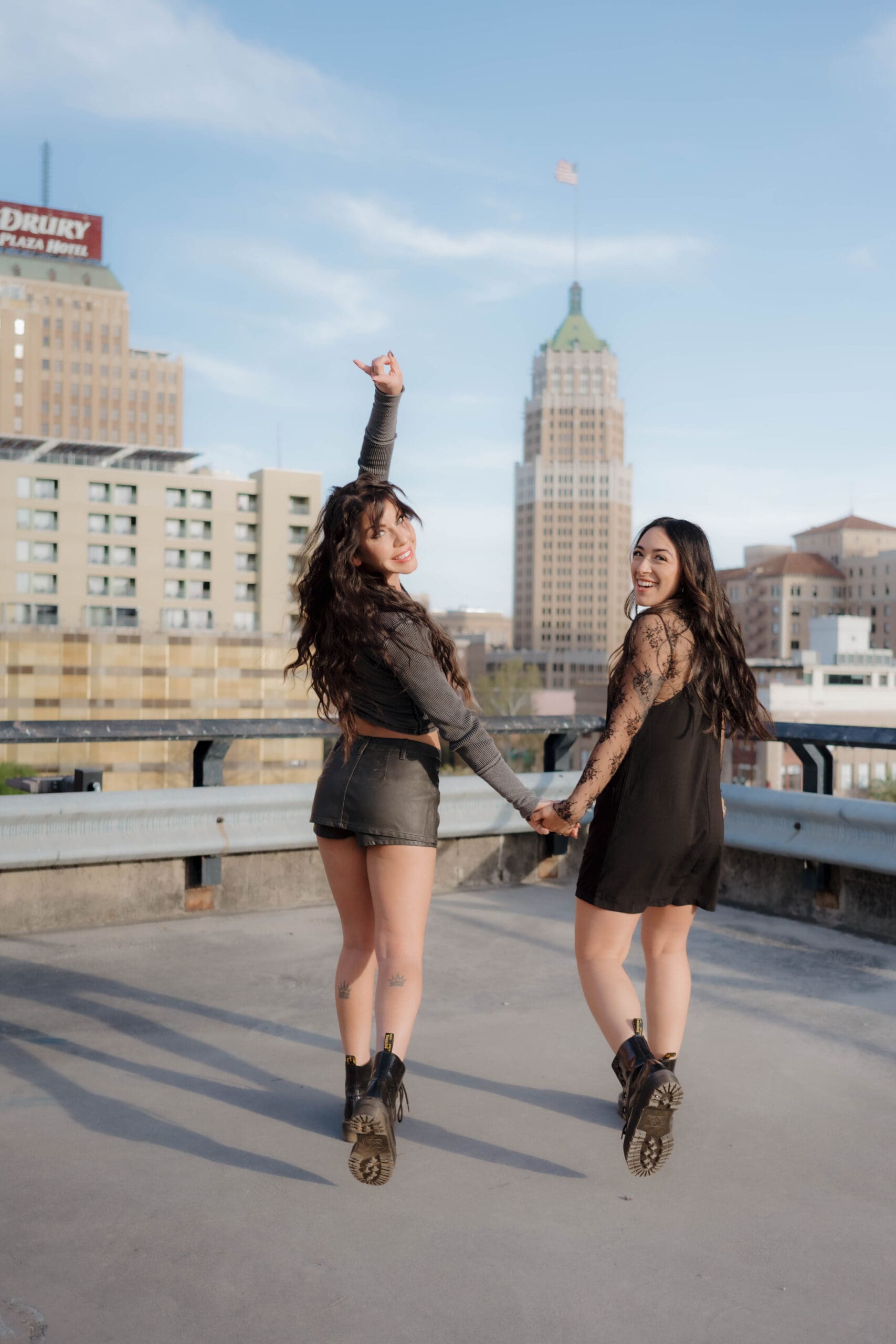 Two female hair stylists walk towards a San Antonio cityscape background.