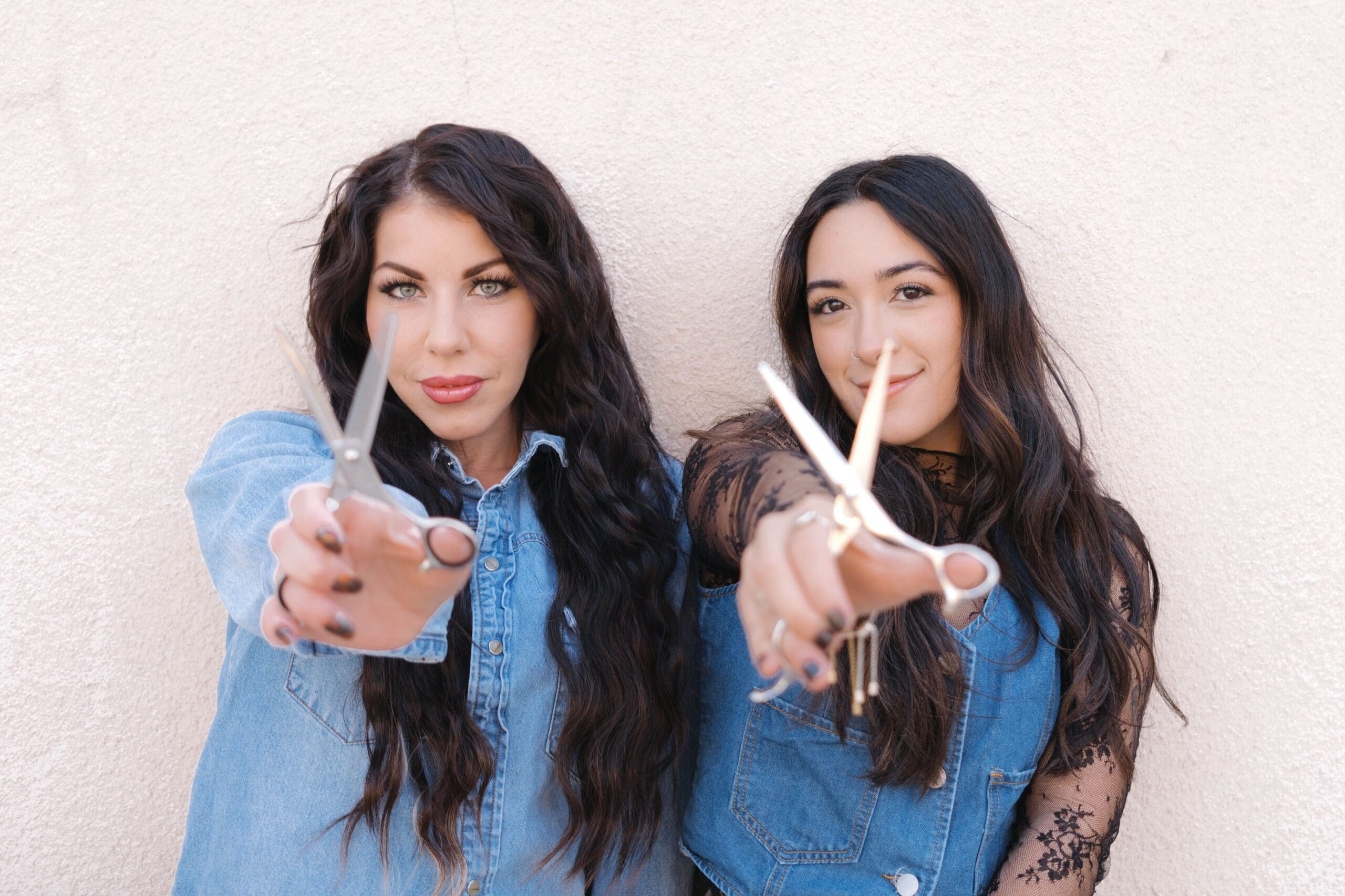 Two female hairstylists pose with scissors for their headshot photography session. 